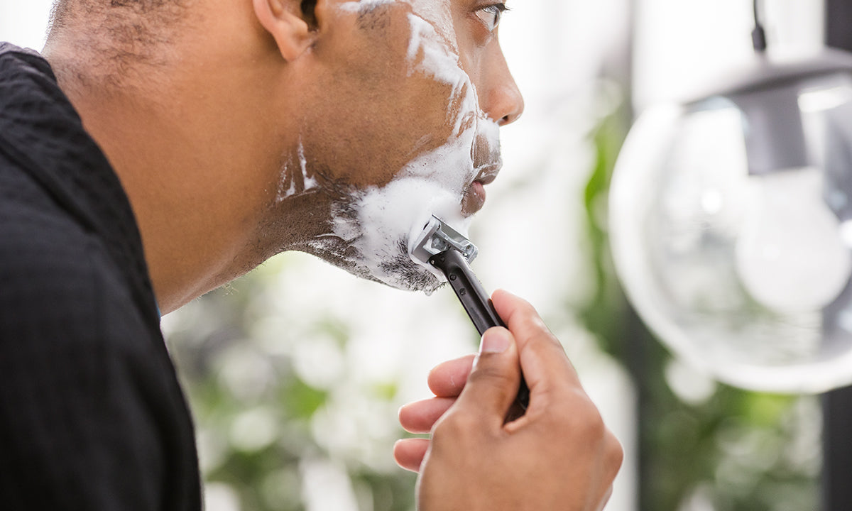 man using razor to shave his face