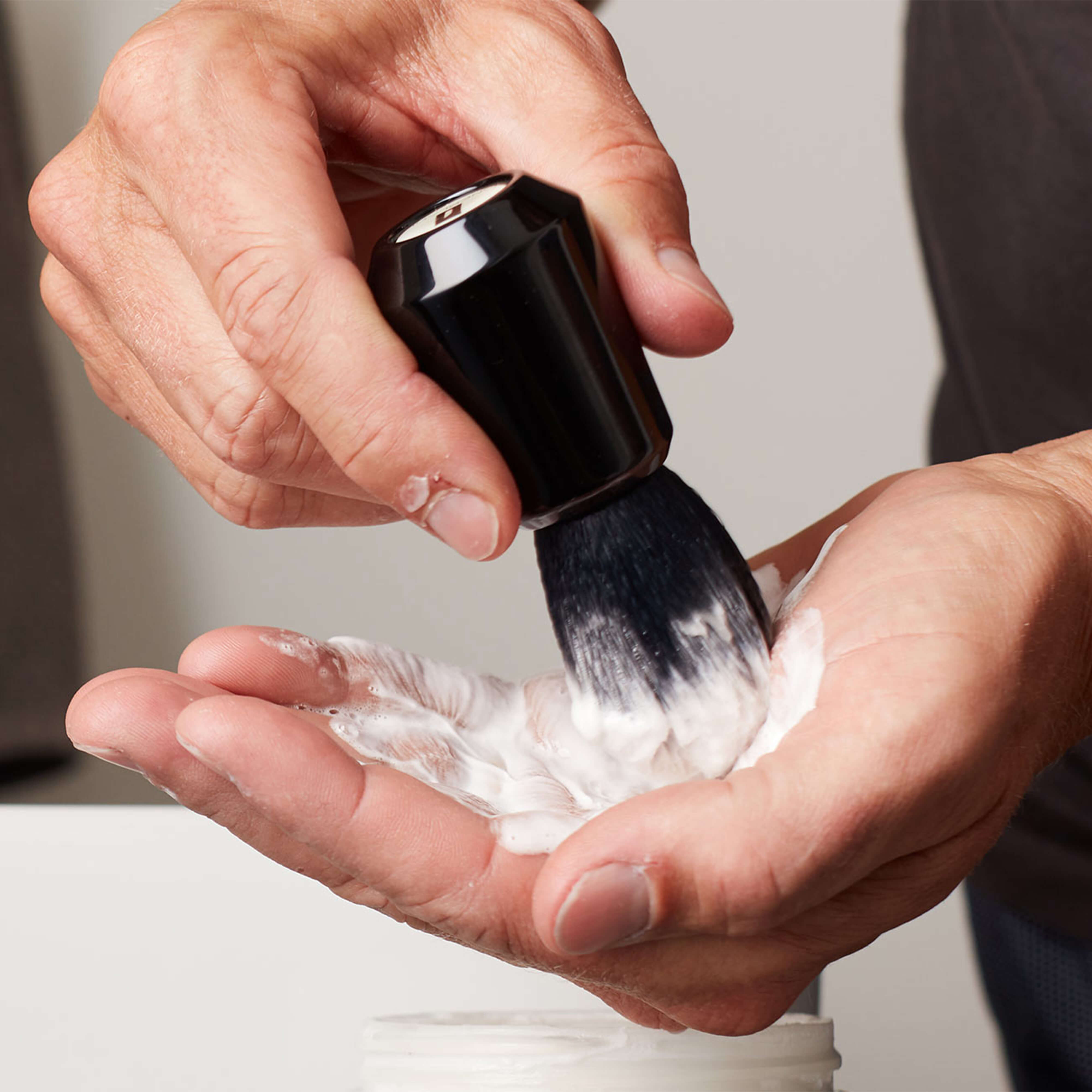 shaving brush creating a lather in a man's hand