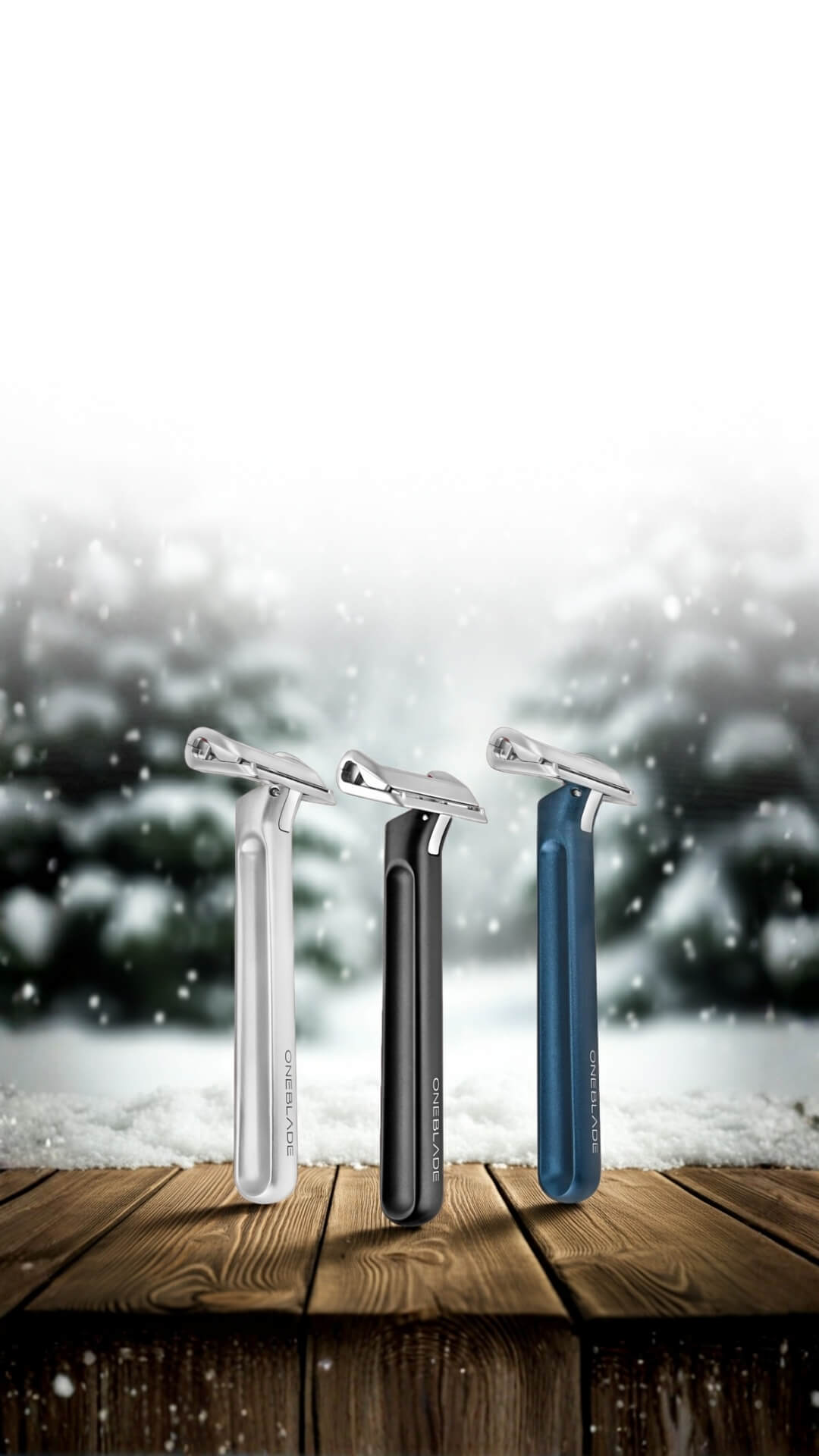 Three razors in silver, black, and blue on a wooden surface with a snowy background.