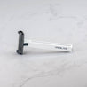 A white Core single blade safety razor on marble surface